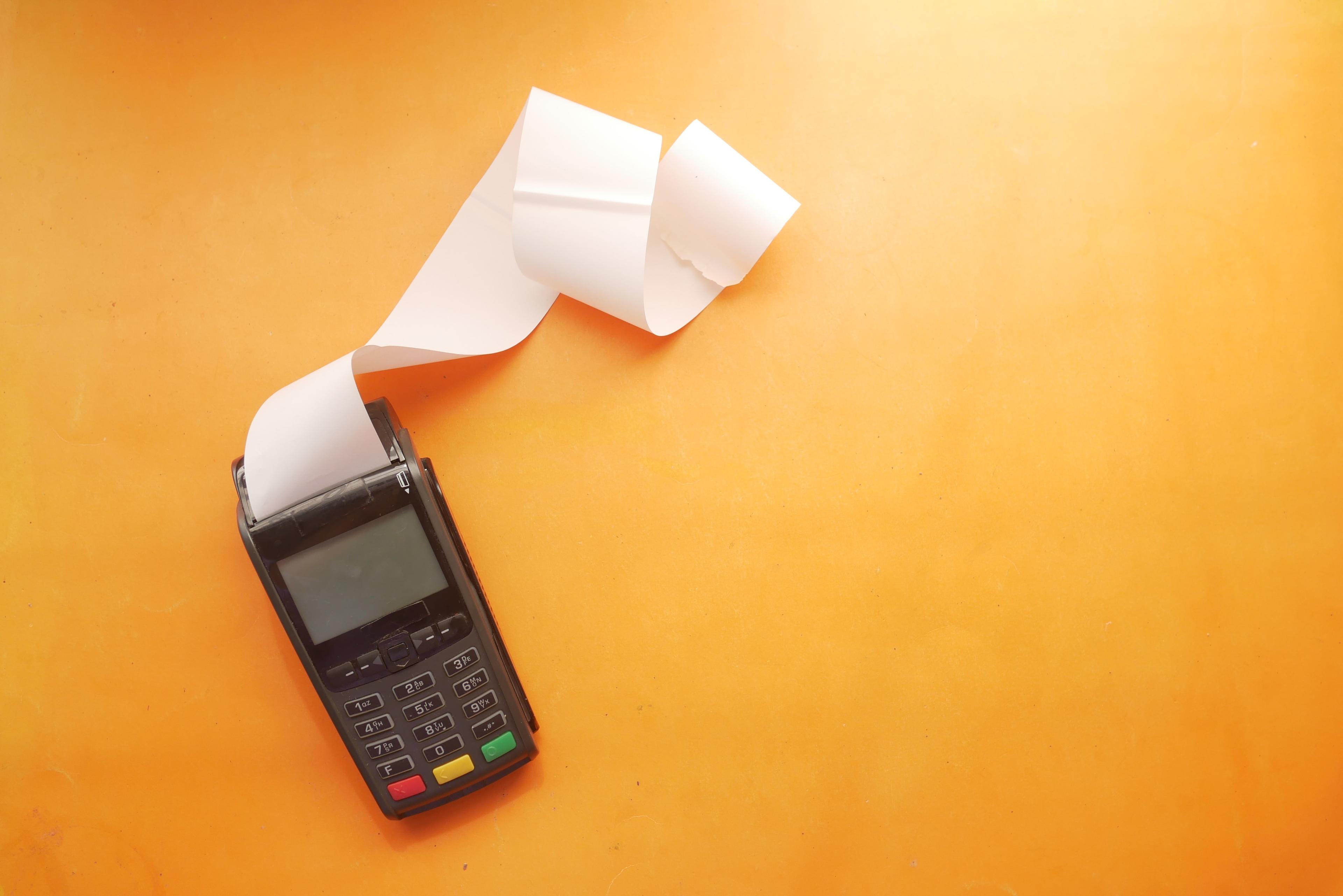 Payment terminal with receipt, representing the one-time payment step for PrintSync Assets.