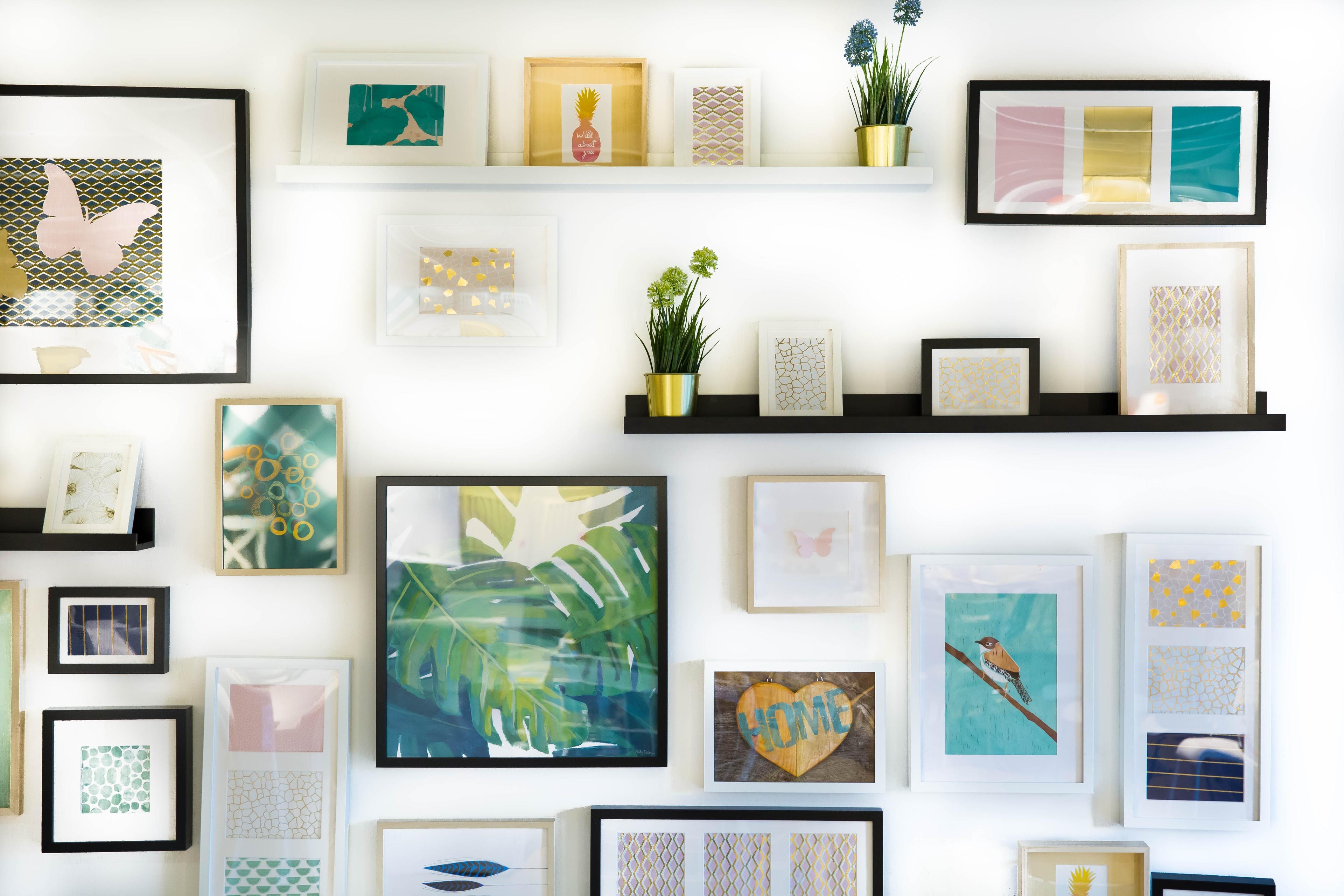 Wall with framed pictures representing the process of managing and uploading images to Printify using Printify Sync Assets.